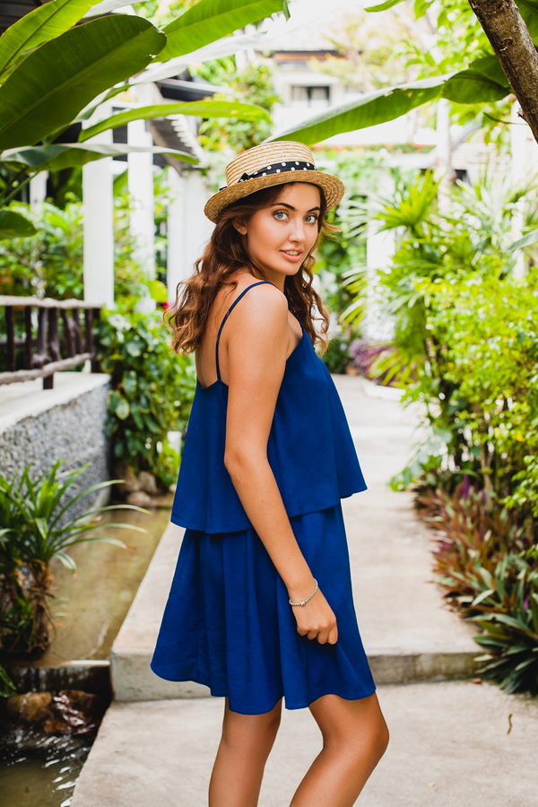 Royal blue layered cami mini dress, back view in a tropical garden